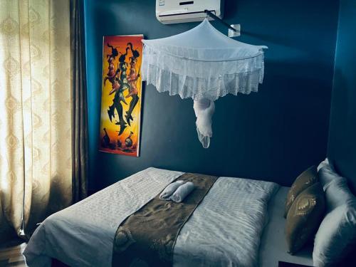 a bedroom with a blue wall with a bed at Elly Villa Hotel in Moshi