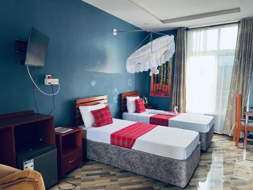 two beds in a room with blue walls at Elly Villa Hotel in Moshi