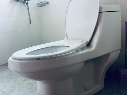 a white toilet in a bathroom with a shower at Elly Villa Hotel in Moshi