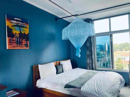 a blue bedroom with a bed with a clear umbrella at Elly Villa Hotel in Moshi