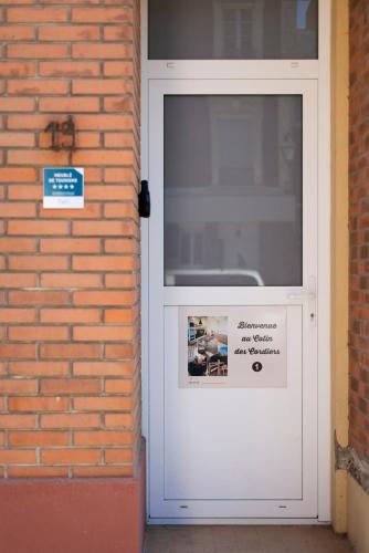 une porte blanche sur un mur en briques avec un panneau sur celui-ci dans l'établissement Le Cotin des Cordiers 1, F3 avec SA PLACE DE PARKING INCLUS, au Tréport