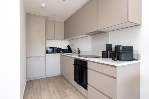 a kitchen with white cabinets and black appliances at 1BR Ideal for Workers at MK Central Train Station with Free Parking and Fast Wi-Fi in Milton Keynes