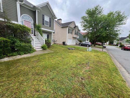 a house with a green lawn in front of a street at The Plush Retreat Marietta With Soaker Tub Walk In Closet in Marietta