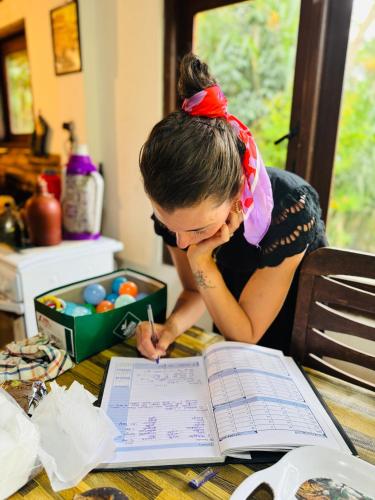 a girl is writing in a book on a table at Moksha eco villa Ella in Ella