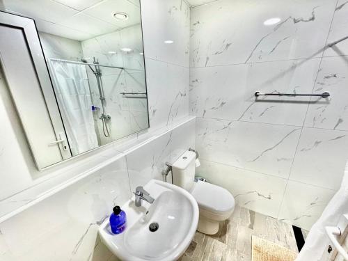a white bathroom with a sink and a toilet at 3 mins walk to ADCB metro in Dubai