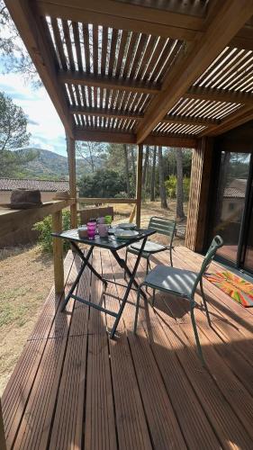 a table and a chair on a wooden deck at Bird in Provence - Cabane dans le Luberon in Cavaillon
