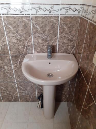 a white sink in a bathroom with brown tiles at Dar Al-Amira - Fnideq Beach Apartment in Fnidek