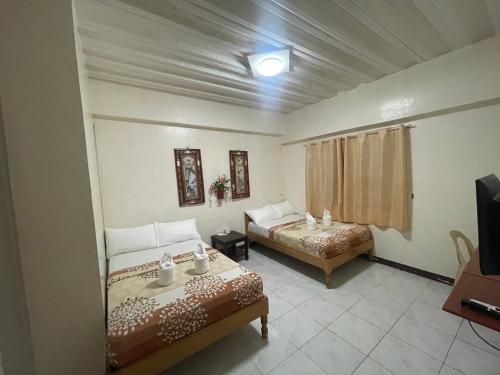 a bedroom with two beds and a tv in it at Constrell Pension House in Tagbilaran City