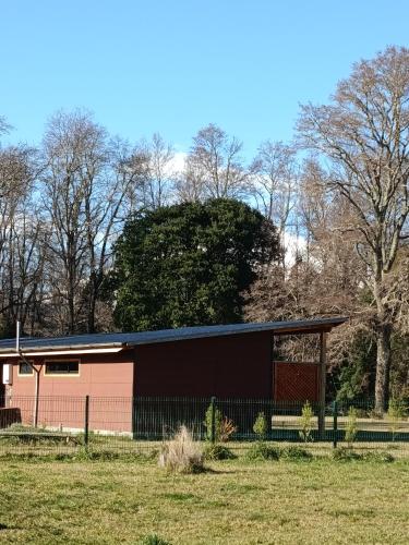 a building with a fence in front of a field at Cabañas Quilacoyan entre Villarrica y Pucon in Villarrica