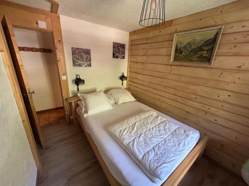 a bed in a room with a wooden wall at Appartement clos du linga pieds des pistes du LINGA in Châtel