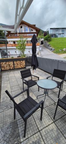 a patio with chairs and tables and an umbrella at Am Sonnenfels in Lermoos
