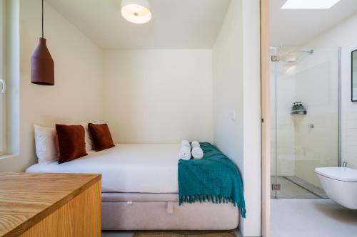 een kleine slaapkamer met een bed en een douche bij Chalet Lídia Lodges in Estoril