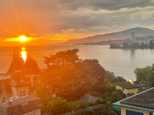 una puesta de sol sobre un cuerpo de agua con edificios en Montreux City Center with Lake View and direct lake access, en Veytaux