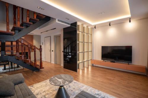a living room with a large television and a staircase at Duplex Penthouse with Jacuzzi in Sarandë