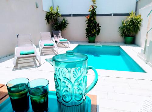 a blue pitcher and two glasses next to a swimming pool at Casa Mediterránia de Palamós amb piscina privada in Palamós