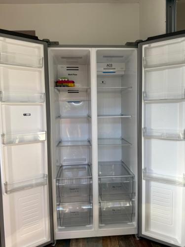 a white refrigerator with its doors open and its shelves at Villa Tamaris in Glanon