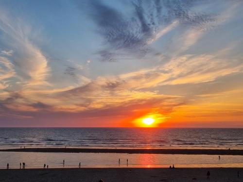 a sunset over the ocean with people on the beach at Villa Tamaris in Glanon