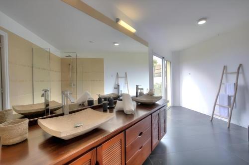 une salle de bain avec deux lavabos et un grand miroir dans l'établissement Villa Stella Australis 4 étoiles, à Petite Île