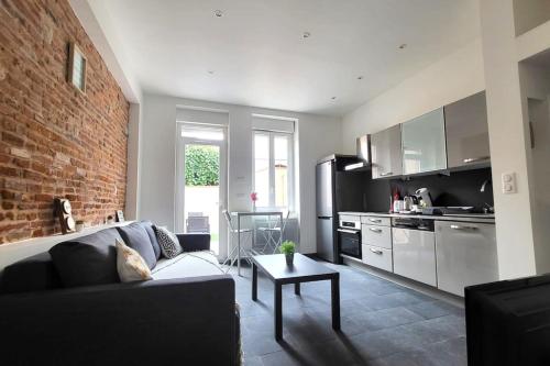 un salon avec un canapé et un mur de briques dans l'établissement Providence Terrasse privée - Proche Gare Sncf, à Toulouse