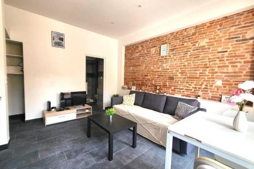un salon avec un canapé et un mur de briques dans l'établissement Providence Terrasse privée - Proche Gare Sncf, à Toulouse