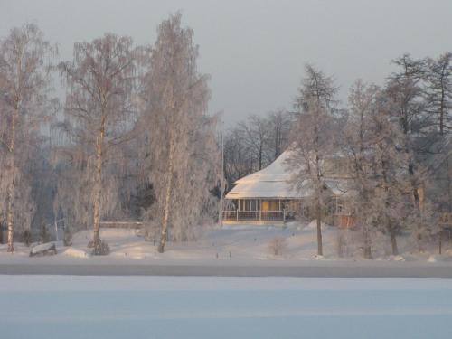 a house with a snow covered roof next to a lake at Villa Huvila in Savonlinna