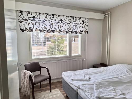a bedroom with a bed and a chair and a window at Jääskän Loma, Kojolapark asunto 2 in Voltti