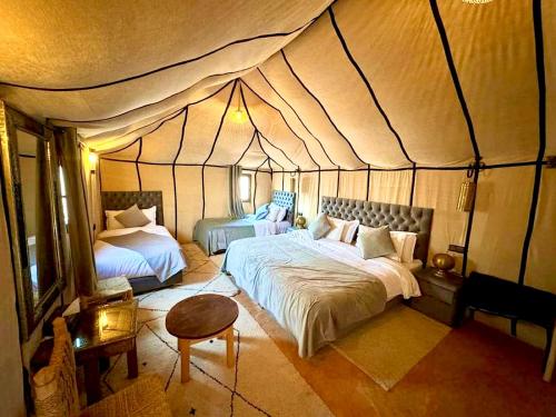 a bedroom with two beds in a tent at Sahara Elegance Camp in Merzouga