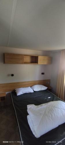 une chambre avec un lit avec deux oreillers blancs dans l'établissement mobil home 235, à Pont-Aven