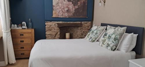 a bedroom with a white bed with a stone fireplace at The Poplars Guest House in Combe Martin
