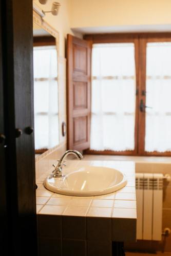 a bathroom with a sink and two windows at Hotel Palacio de Caranceja in Reocín