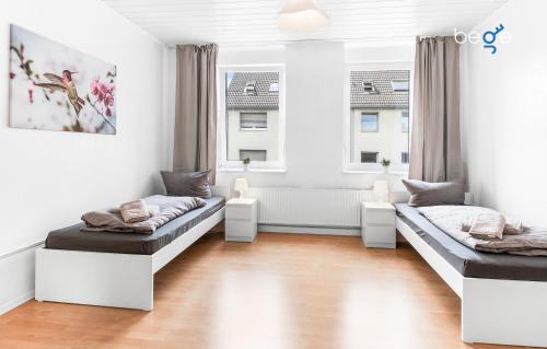a living room with two beds and two windows at BEGE APARTMENTS Flatbox in Herten