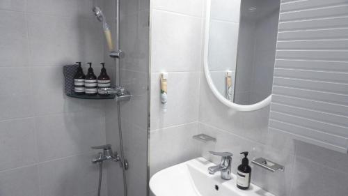 a white bathroom with a sink and a mirror at Maru Stay in Seoul