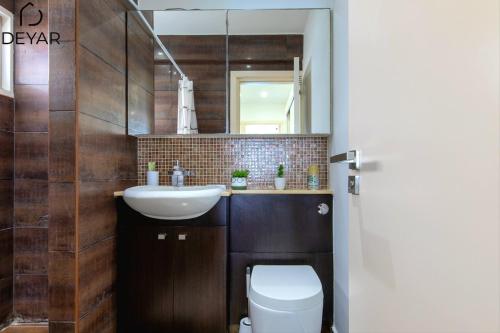 a bathroom with a sink and a toilet and a mirror at Sea View Apartment with Pool - Relax by the Coast in Larnaka