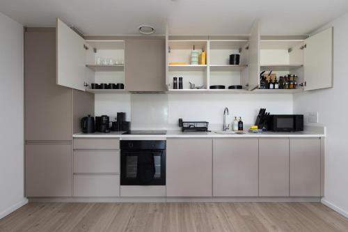 a white kitchen with white cabinets and appliances at Quiet and Large with Free Parking Ideal for Families and Business Stays in Milton Keynes