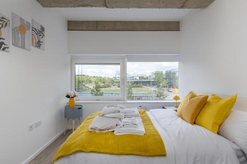 a bedroom with a large white bed with yellow accents at Quiet and Large with Free Parking Ideal for Families and Business Stays in Milton Keynes