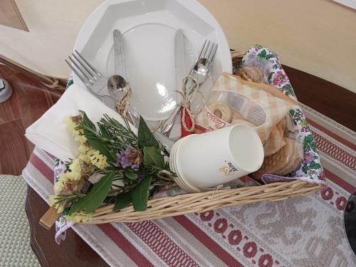 a basket with a plate and utensils and flowers at Tenda romantica nel Noccioleto in Castellero