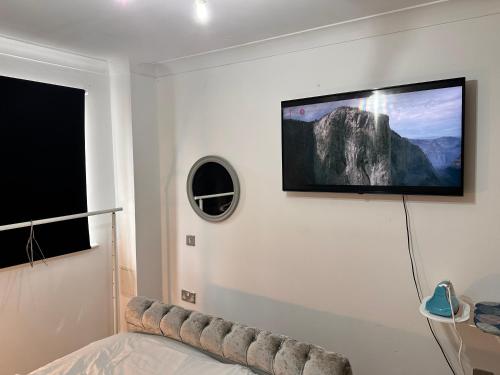 a room with a tv on a wall with a bed at Enjoy city living in this one-bedroom flat, complete with a balcony and secure parking in Birmingham city center in Birmingham