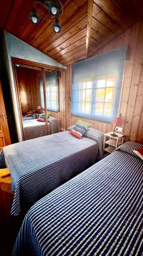 two beds in a room with wooden walls at Apartamentos Numancia in Garray