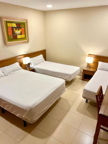 a room with two beds and two tables and two lamps at Hostal Aeropuerto in Madrid