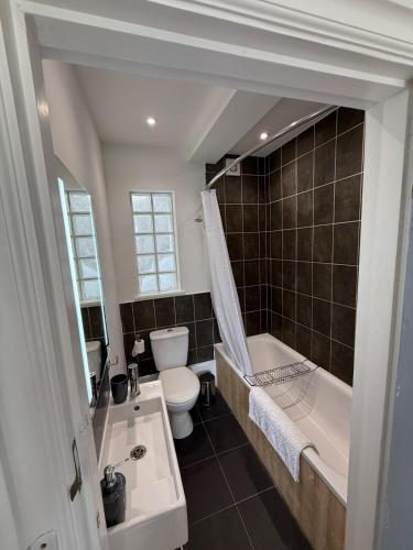a bathroom with a tub and a toilet and a sink at Modern Town Centre Flat in St Austell