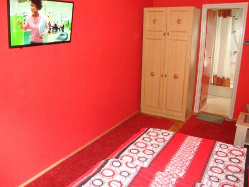 a room with a red wall with a tv on the wall at FANNI vízközeli, klimatizált Vendégház in Balatonboglár