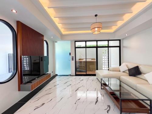 a living room with a couch and a tv at Modern ZEN Vibe 3BR Pool Villa Phuket in Ban Tha Khreng