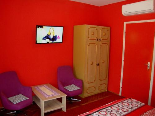 a red room with two chairs and a table and a tv at FANNI vízközeli, klimatizált Vendégház in Balatonboglár