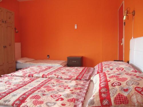 a bedroom with two beds and an orange wall at FANNI vízközeli, klimatizált Vendégház in Balatonboglár