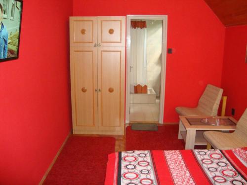 a red bedroom with a bed and a cabinet and a chair at FANNI vízközeli, klimatizált Vendégház in Balatonboglár