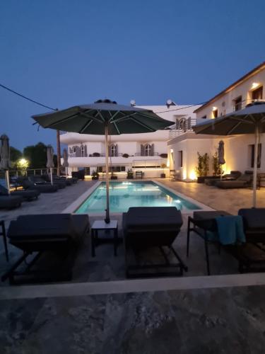 a swimming pool with chairs and an umbrella at La vie luxury suites in Megalochori