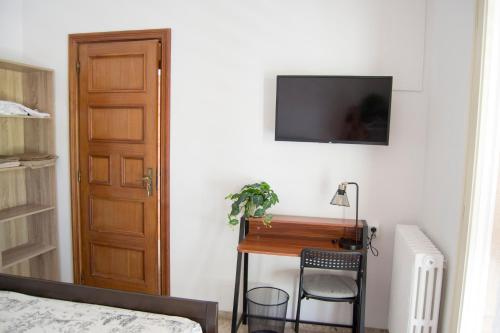 a bedroom with a desk and a television on a wall at Cal Kim in Martorell