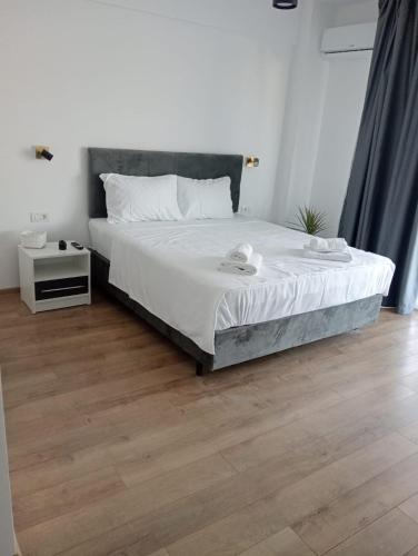 a bedroom with a bed with white sheets and a wooden floor at Nicholas Studio Saturn in Mangalia