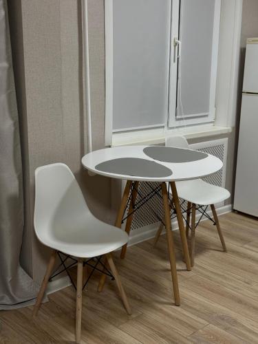 two white chairs and a table in a kitchen at Апартаменты в самом центре города in Balqash