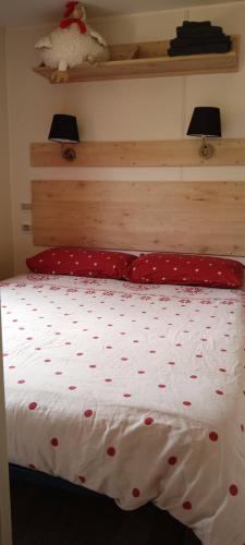 - un lit avec des draps rouges et blancs et des oreillers rouges dans l'établissement Roulotte Bigoudenne, à Tréméoc